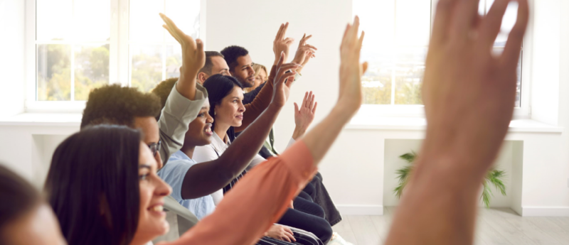 Adults with their hands raised in training session.